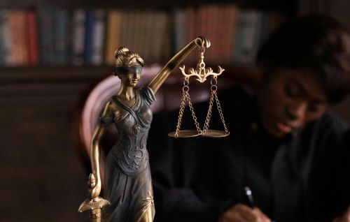 Close-up of Lady Justice figurine on a lawyer's desk with books and documents.