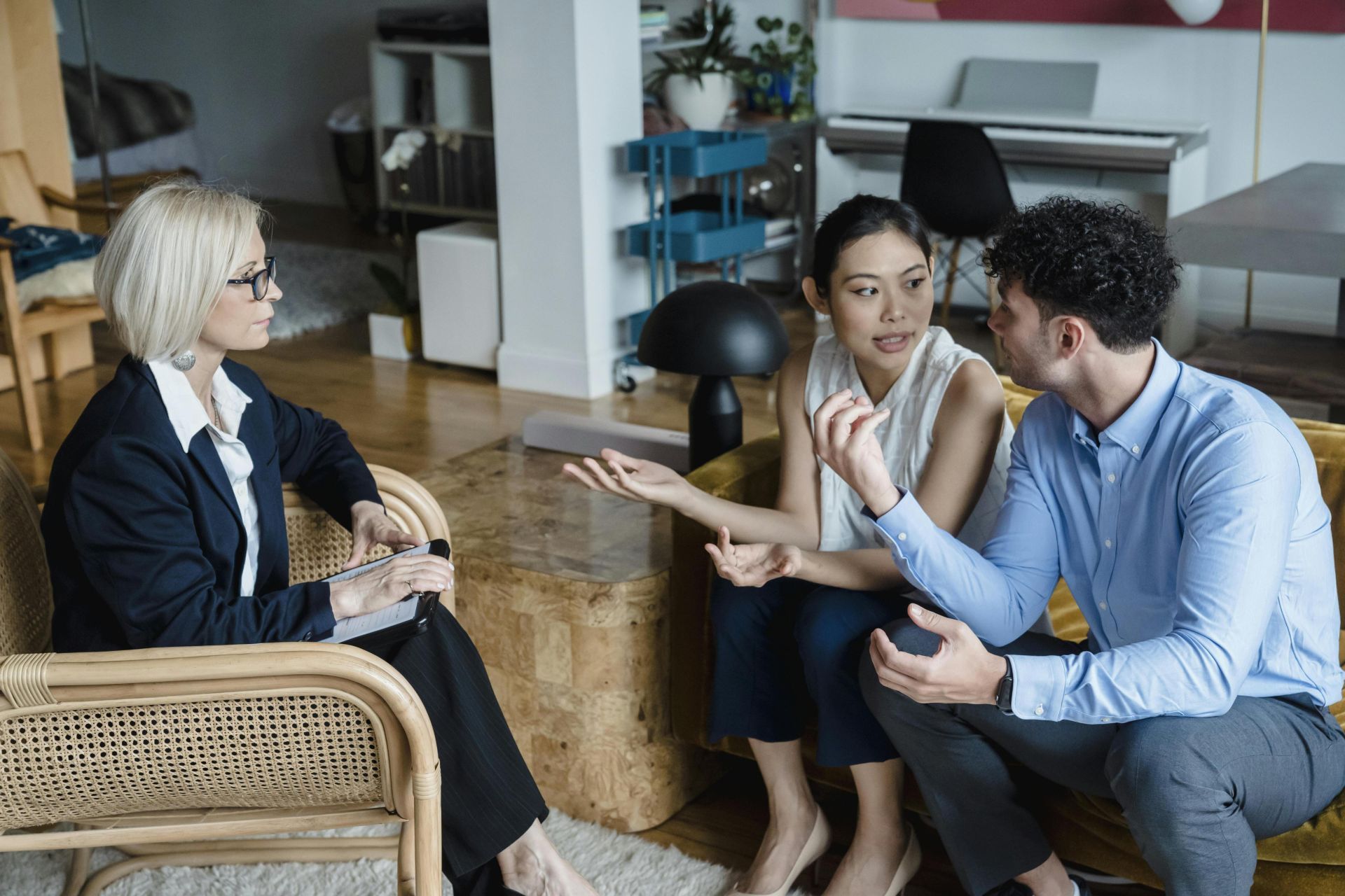 Couple having a discussion with a counselor in a modern living room setting.